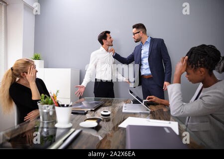 Dissatisfied CEO Shouting At His Young Male Worker For Bad Performance In Front Of Coworkers Stock Photo
