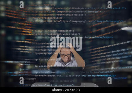 Young male web developer getting angry and frustrated while working on his project. Working at night shift. HTML Codes. Stock Photo