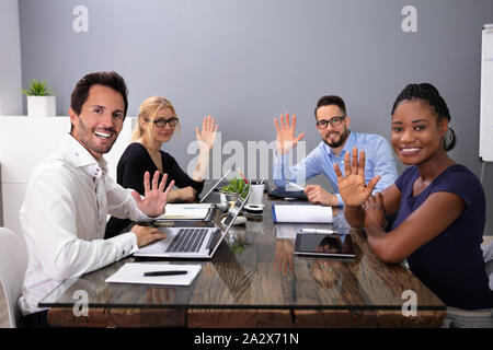 Happy Young Businesspeople Waving Hands During A Meeting Conference In The Office Stock Photo