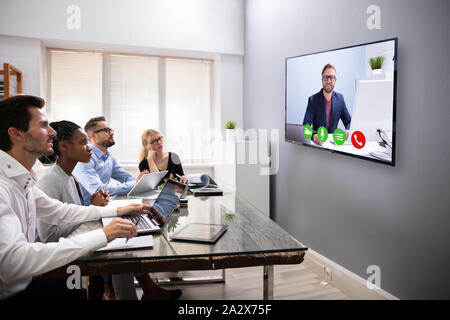 Businesspeople Sitting In A Conference Room Looking At Computer Screen Stock Photo