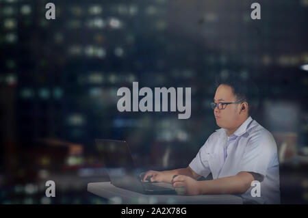 Smart student doing his research. Diligent man working overnight. An industrious businessman. Working night shift at the office. City life of a man. Stock Photo