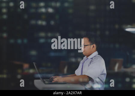 Working overnight. Student studying and doing homework with laptop at night. Hardworking office staff. Diligent employee. Industrious businessman. Stock Photo