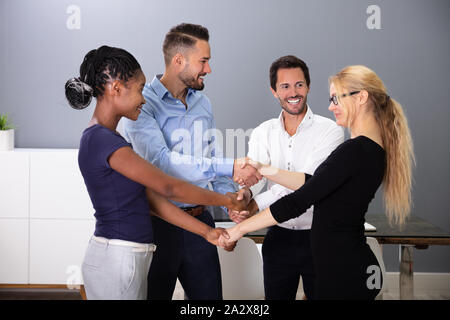 Group Of Multi Racial Businesspeople Shaking Hands With Each Other In Office Stock Photo