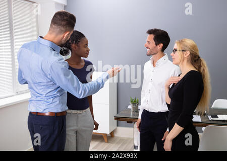 Young Male Executive Introducing New Hire Employee To Corporate Team At Group Meeting Stock Photo