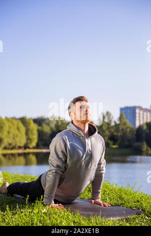 Inspired man doing yoga asanas in city park. Fitness outdoors and life balance concept. Close up Stock Photo