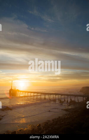 An industrial pier sits off the coast of California at sunset where seals sleep in a wildlife preserve. Stock Photo
