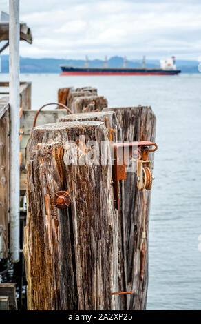 Old rotten pier with rotten loose piles driven into the bottom of the bay and metal rusty ties for a reliable bundle of parts of the pier at the mouth Stock Photo