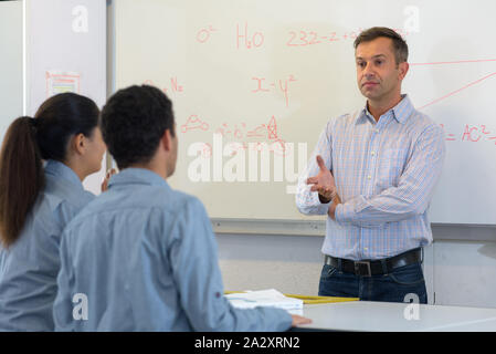 students and teacher with math formulas on white board Stock Photo