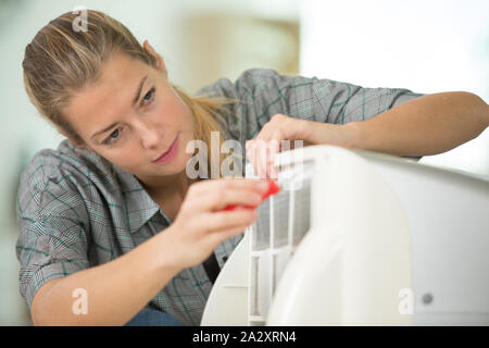 female technician cleaning air conditioner indoors Stock Photo