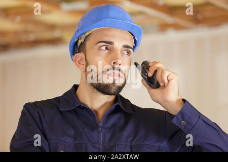 workman wearing overalls using walkie talkie Stock Photo