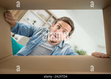 astonished man looking down into cardboard box Stock Photo