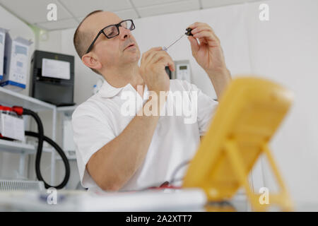 electrician checking socket voltage using multimeter Stock Photo