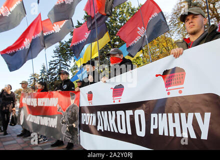 Kiev, Ukraine. 02nd Oct, 2019. Protesters hold flags while standing behind banners during the demonstration.Ukrainian nationalists of the far-right party rally against the sale of land outside the Ukrainian Parliament following the newly appointed Ukrainian Prime Minister, Oleksiy Honcharuk's early announcement of a pending reform where Ukraine will begin selling its land, according the local media. Credit: SOPA Images Limited/Alamy Live News