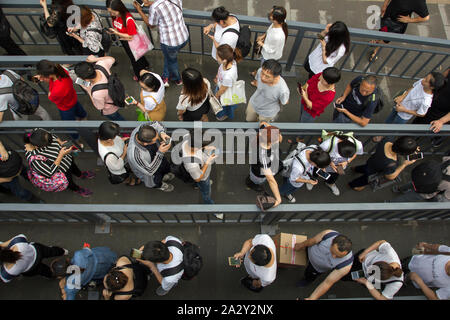 A queue of commuters preoccupied with their smartphones at a bus station in Beijing, China, seen during evening rush hour on Wednesday, July 17, 2019. Stock Photo