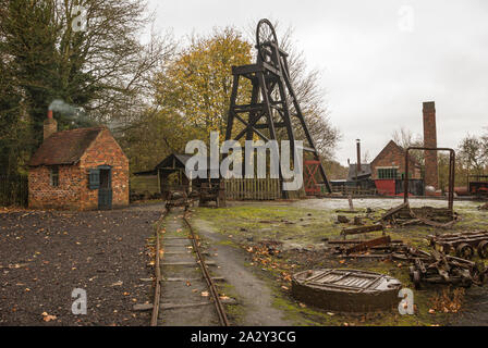 Old pit head at top of mine shaft with narrow-gauge railway tracks in foreground Stock Photo
