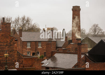 Industrial rooftop scene with chimneys and smoke Stock Photo