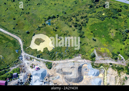 Aerial view of a small plant for the production and cleaning rubble and cement near the heaps of building materials from the pipe of which gray smoke Stock Photo