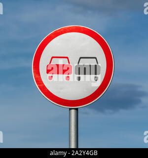 No overtaking road traffic sign on background of blue sky with clouds. Warning and information road traffic street sign, compliance with rules Stock Photo