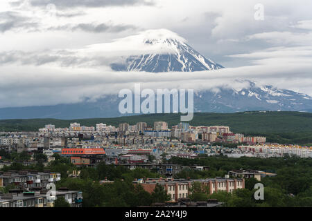 Summer city scape of Kamchatka Peninsula, residential building and urban development of Petropavlovsk-Kamchatsky City on background of active volcano Stock Photo