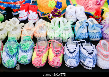 Rows of colorful knitted baby shoes on black background Stock Photo