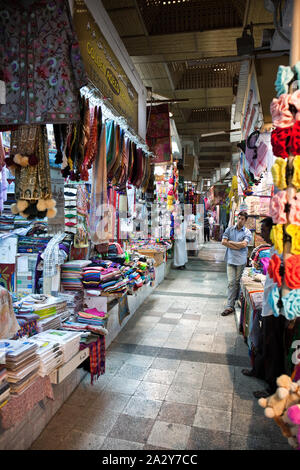 Variety of traditional carpets and clothing for sale on the souk of Muscat, Oman Stock Photo