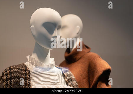 Two mannequins in a shop window dressed in warm clothes for autumn and winter. Seasonal sale. Selective focus. Stock Photo