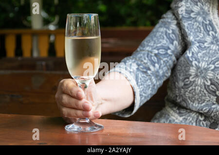 Close up view of modern senior lady hands holding a glass of white wine Stock Photo