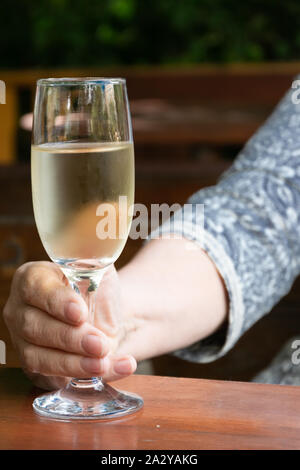 Close up view of modern senior lady hands holding a glass of white wine Stock Photo