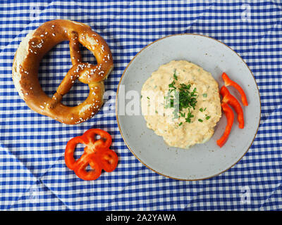 traditionally bavarian food appetizer with brezen and cheese paste called obazda on blue white checkered tablecloth Stock Photo