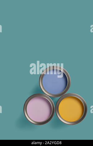 Blue, pink and yellow paint tins on a colored background with copy space. Blue and pink for a boy and girls bedroom, and yellow for the neutral. Stock Photo