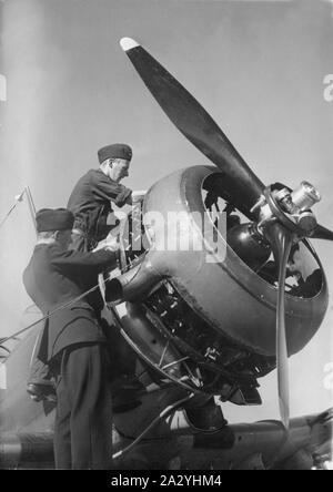 Airplane engineers.Three mechanics are performing the important last minute check of engine details before start. The airplane is a swedish single propeller engine light bomb and survaillance unit model B5. The swedish company Saab Svenska Aeroplan AB produced this airplane on license from American Northrop and their model 8A-1.  Picture taken in the 1940s during the second world war. Stock Photo