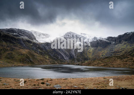Stunning dramatic Winter landscape image of Llyn Idwal and snowcapped Glyders Mountain Range in Snowdonia Stock Photo