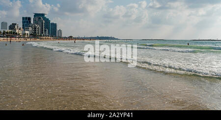 bathers and tourists enjoying a perfect weather on a tel aviv beach with resort hotels and jaffa port in the background Stock Photo