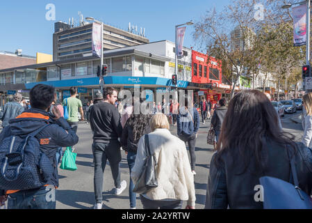 A large group of people crossing a road at an intersection in the shopping precinct of the Sydney suburb of Chatswood in Australia Stock Photo