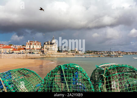 Seafront promenade with fishing nets, and Praia da Ribeira beach or Praia dos Pescadores on the seafront of Cascais, popular resort in Portugal. Stock Photo