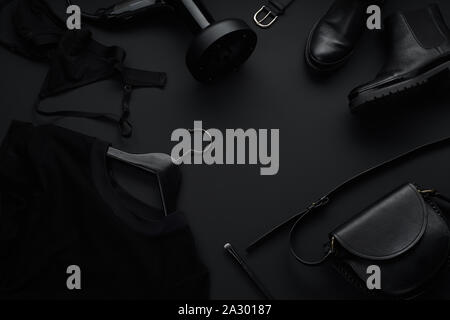 Black monochromatic flatlay on black background. Clothes, accessories and beauty equipment. Black friday sale concept Stock Photo
