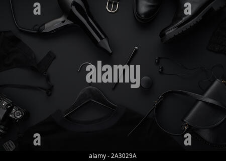 Black monochromatic flatlay on black background. Clothes, accessories and beauty equipment. Black friday sale concept Stock Photo