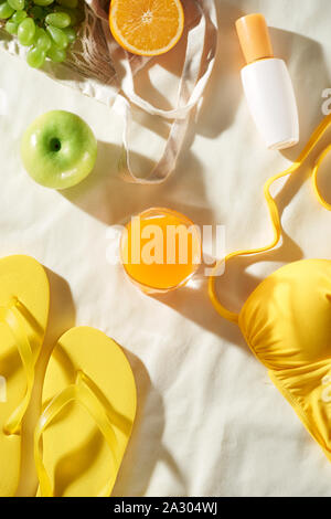 Summertime picnic on white background with fruit bag, flip-flop, sin cream and juice, flat lay Stock Photo