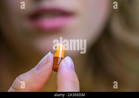 A capsule held between two fingers. Stock Photo