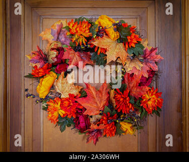 An autumn inspired wreath hanging on an old wooden door. Stock Photo