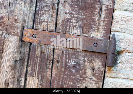 Window detail of rural house, with cracked paint and rusty hinges, on brick wall and ancient stones. Stock Photo