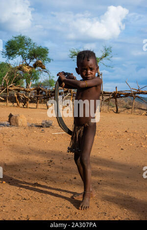 Turmi, Ethiopia - Nov 2018: Hamer tribe kid posing with the tire, common toy in the region. Omo valley Stock Photo