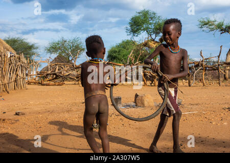 Turmi, Ethiopia - Nov 2018: Hamer tribe kids playing with the tire. Omo valley Stock Photo