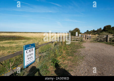 The view across the marshes to the North Sea and a sign to Wiveton Hall cafe, 15 mins walk from Blakeney, Wiveton, North Norfolk, UK Stock Photo