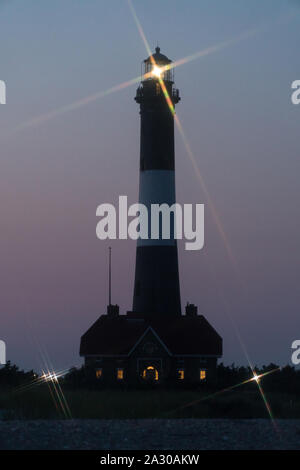 Fire Island lighthouse beacon cross star effect from beacon light shining over Robert Moses beach at night time signaling shoreline to ocean boats tra Stock Photo