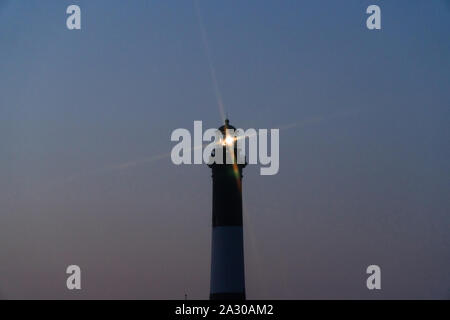 Fire Island lighthouse beacon cross star effect from beacon light shining over Robert Moses beach at night time signaling shoreline to ocean boats tra Stock Photo