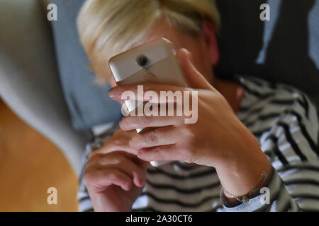 Munich, Deutschland. 04th Oct, 2019. Issues image, photo icon; Cell phone addiction, smartphone addiction, junkie, woman looks spellbound also her smartphone. | usage worldwide Credit: dpa/Alamy Live News Stock Photo