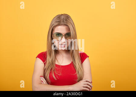 young blonde girl in red t-shirt over isolated orange background shows emotions Stock Photo