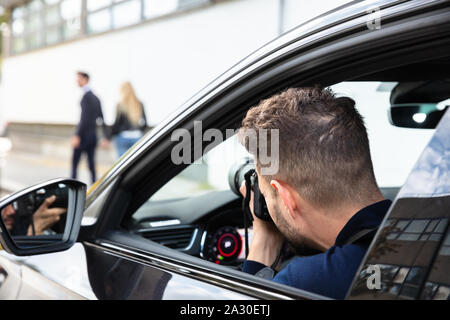 Private Detective Taking Photos Of Man And Woman On Street Stock Photo