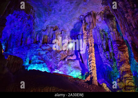 Reed Flute cave of Guilin, China, with beautiful and dramatic mineral rock formations with stalactites and stalagmites colored with artificial lightin Stock Photo
